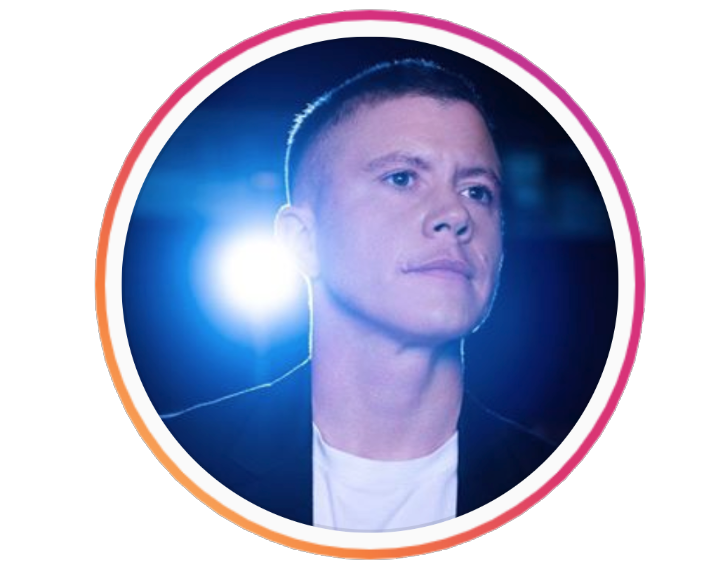   Ocean looks at the camera off to the left, he wears a white t-shirt, there is a spotlight behind him